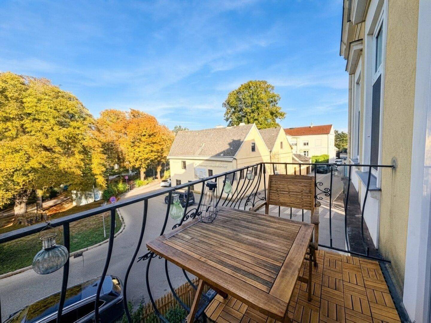 Gemütlicher Balkon mit Holztisch und Stühlen, bietet Blick auf die grüne Umgebung.