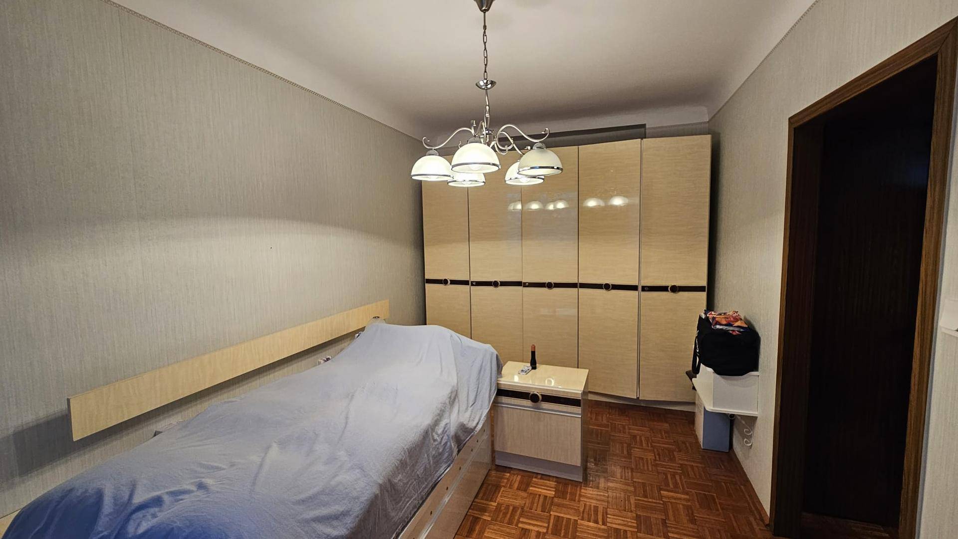 Schlafzimmer mit Bett, Parkettboden und einem großen Einbauschrank für ausreichend Stauraum.