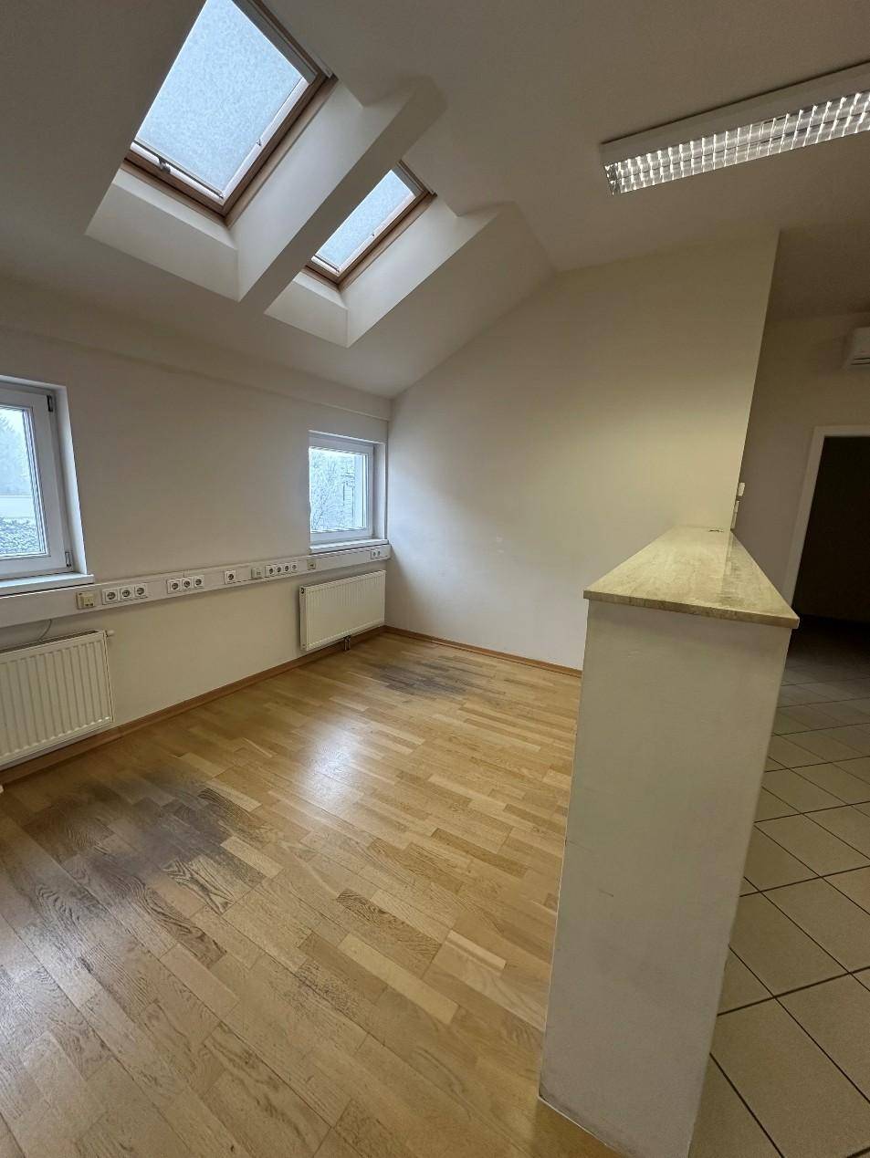 Geräumiges Zimmer mit Holzboden, Dachfenstern und einem Heizkörper, das viel Tageslicht erhält.