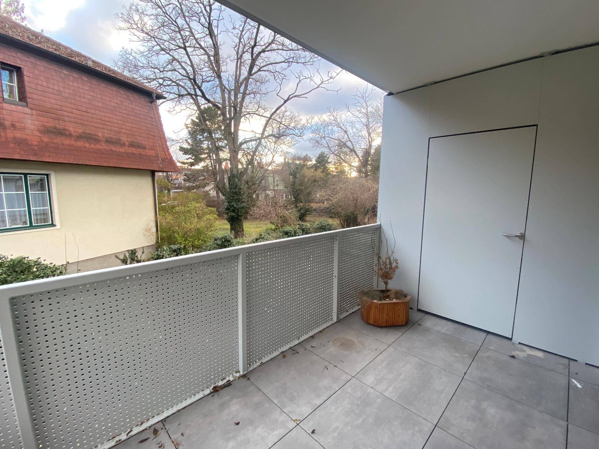 Heller Balkon mit Blick ins Grüne und einer modernen, perforierten Brüstung.