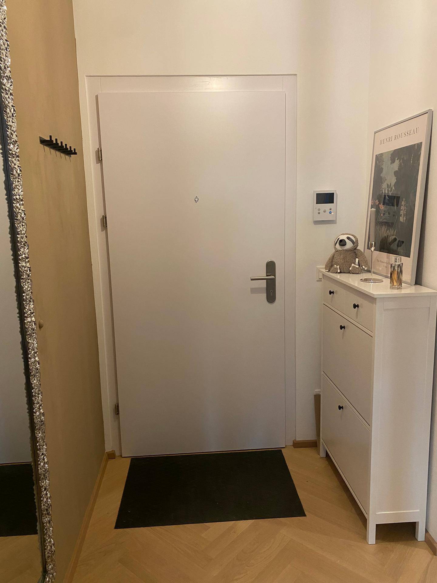 Eingangsbereich mit weißer Tür, Schuhschrank und modernem Parkettboden.