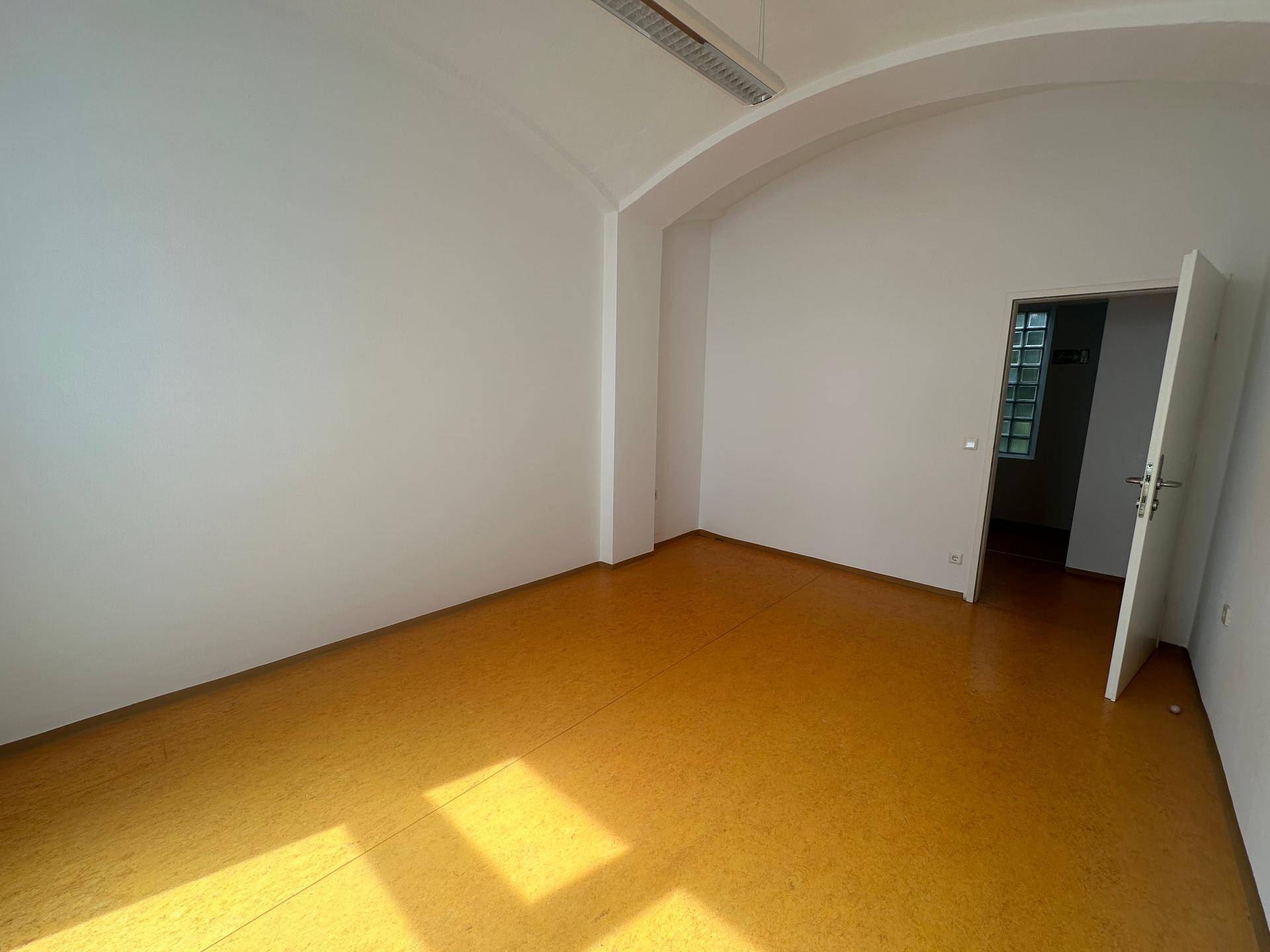 Leerer Büroraum mit orangefarbenem Linoleumboden und gewölbter Decke, bereit zur Nutzung.