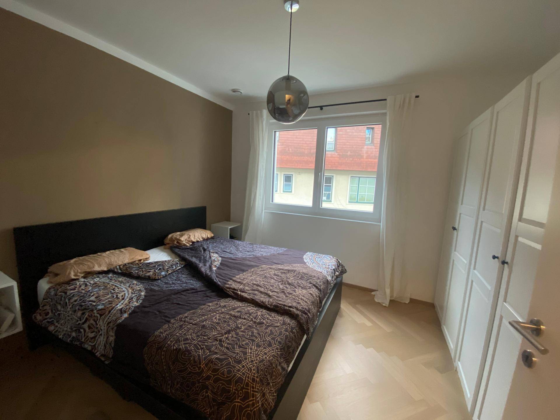 Gemütliches Schlafzimmer mit Doppelbett, Einbauschränken und Parkettboden.