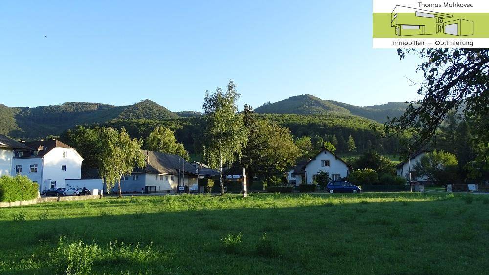 Blick auf die umliegende Wohnbebauung mit grünen Wiesen und Bergen im Hintergrund.