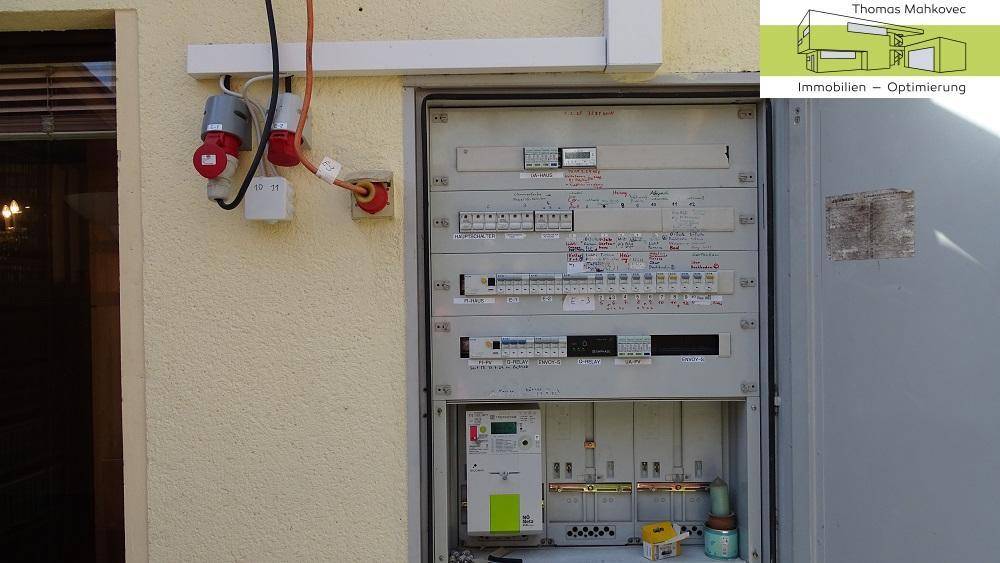 Außenliegender Sicherungskasten mit verschiedenen elektrischen Anschlüssen und Steckdosen an der Fassade.
