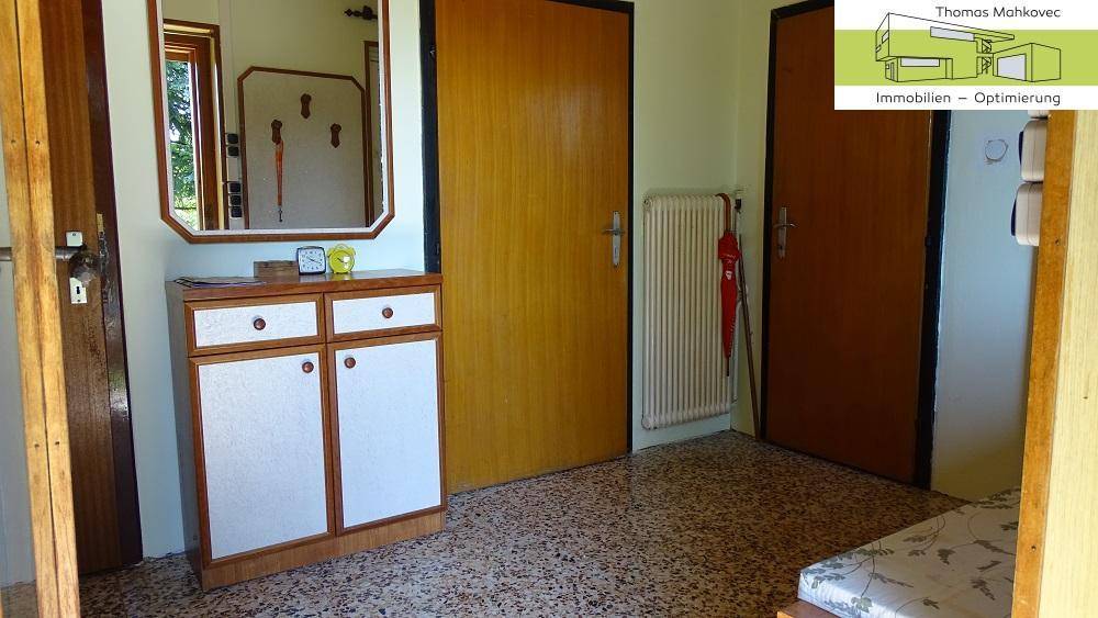 Flur mit Terrazzoboden, Garderobenschrank und Spiegel.