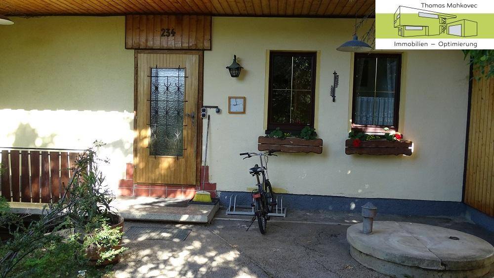 Detailansicht des Hauseingangs mit Holztür und Fensterkästen.