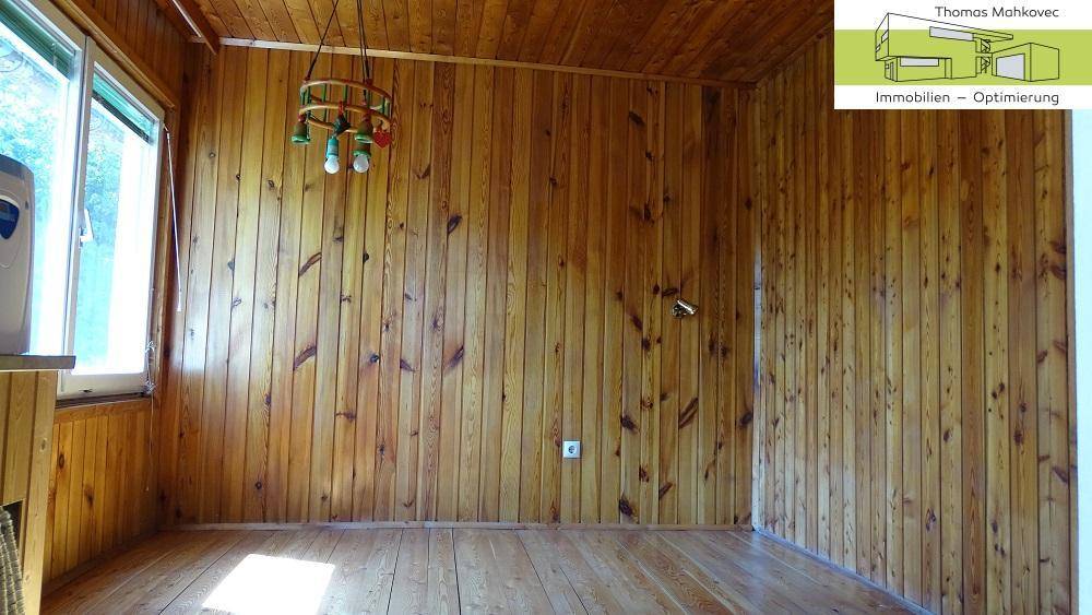 Raum mit vollständiger Holzvertäfelung an Wänden und Decke, hell durch Fenster.
