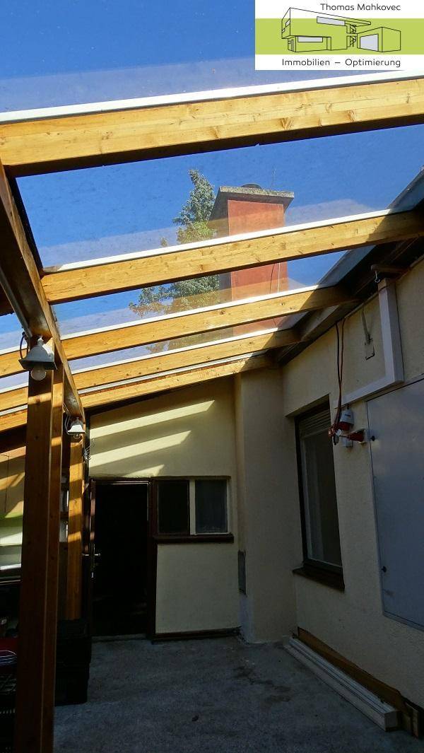 Überdachter Gang oder Wintergarten mit Holzkonstruktion und Glasdach.