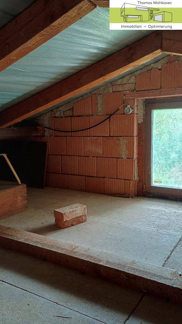 Rohbau-Dachboden mit Holzbalken und Ziegelmauerwerk, bietet Potenzial für Wohnraum.