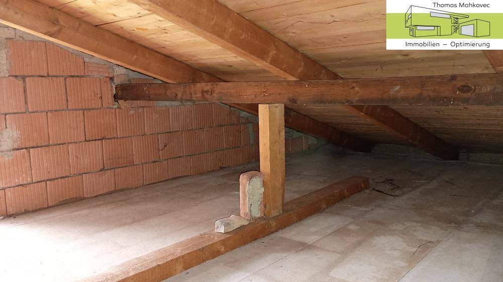 Unfertiger Dachboden mit sichtbaren Holzbalken und Ziegelwänden, bereit für Ausbau.