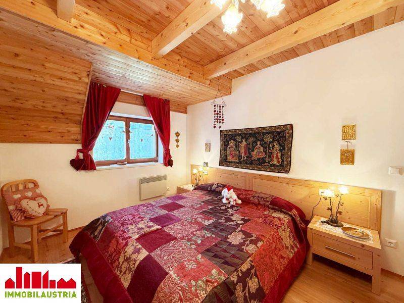 Gemütliches Schlafzimmer mit Holzbett, Dachschräge und traditioneller Dekoration.