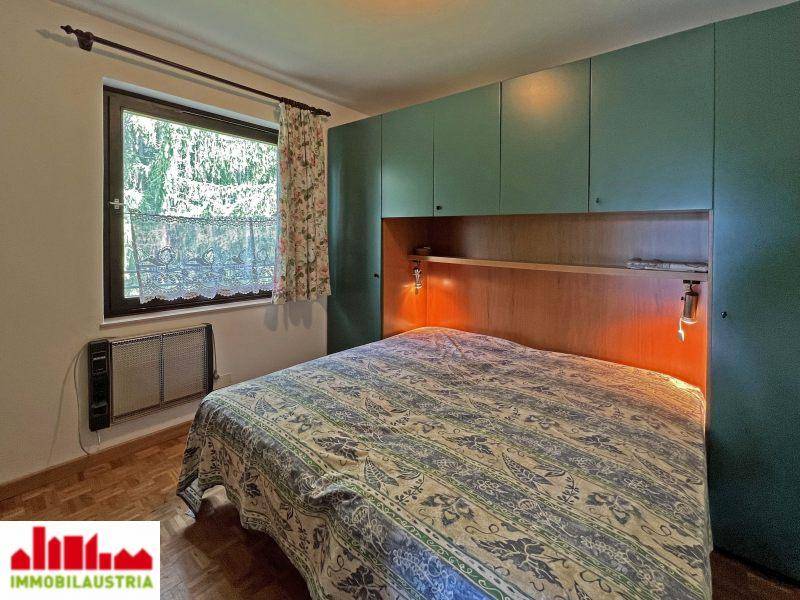 Schlafzimmer mit Doppelbett, integrierten Schränken und einem Fenster mit Blick ins Grüne.