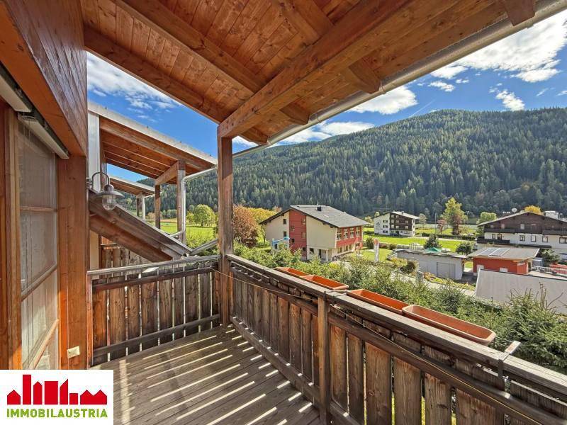 Geräumiger Holzbalkon mit weitem Blick auf die umliegende Natur und die Berglandschaft.