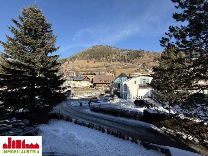 Panoramablick auf die verschneite Berglandschaft und die umliegenden Gebäude an einem sonnigen Tag.