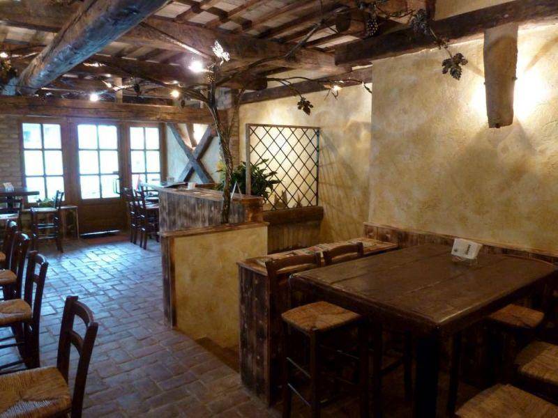 Gemütlicher Restaurantbereich mit Holztischen, Ziegelboden und großen Fenstern, umgeben von rustikalem Dekor.