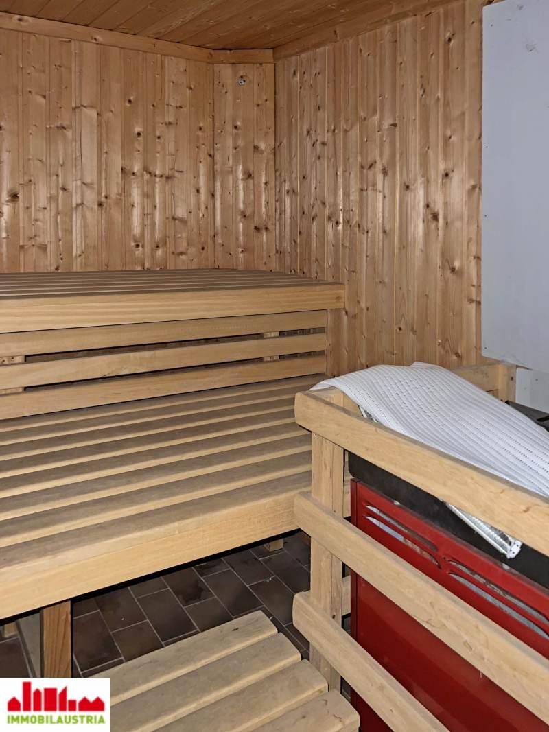 Traditionelle Holzsauna mit mehreren Sitzebenen und einem sichtbaren Saunaofen.