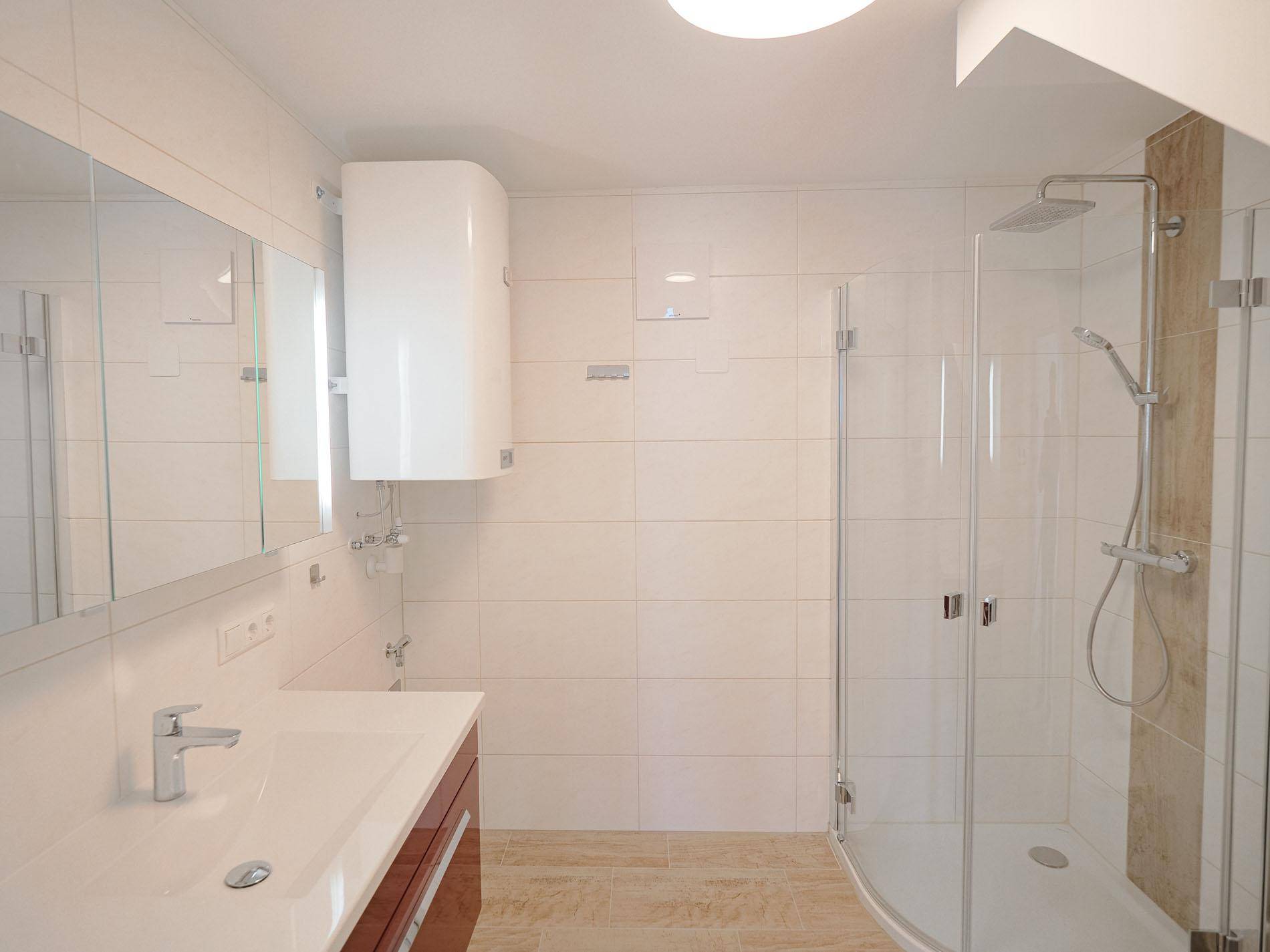 Helles Badezimmer mit großem Spiegel, Einzelwaschbecken und moderner Duschkabine.