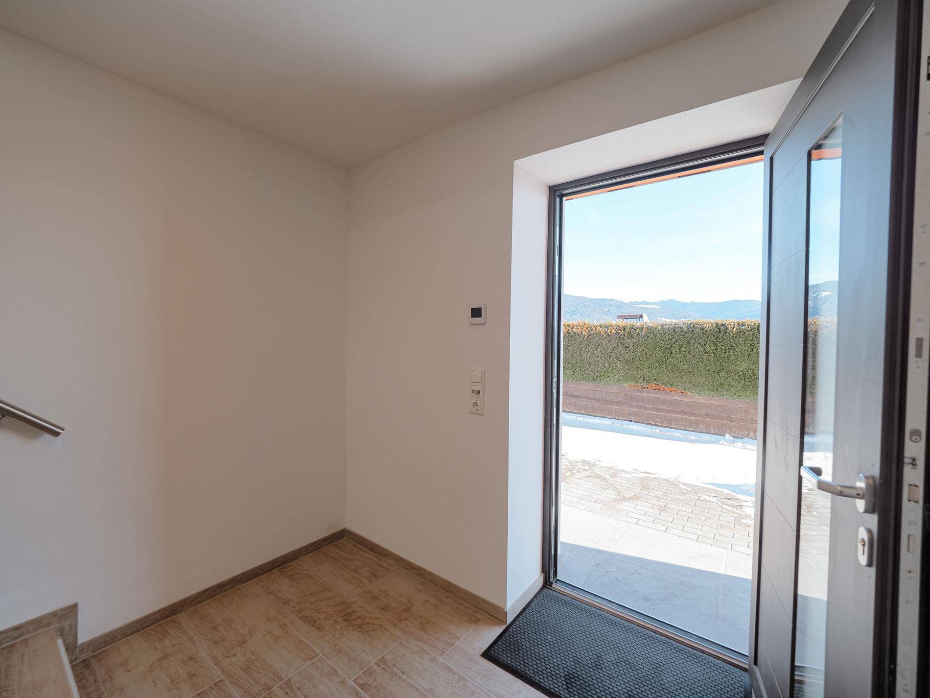 Eingangsbereich mit Fliesenboden und großer Glastür, die viel Tageslicht hereinlässt.