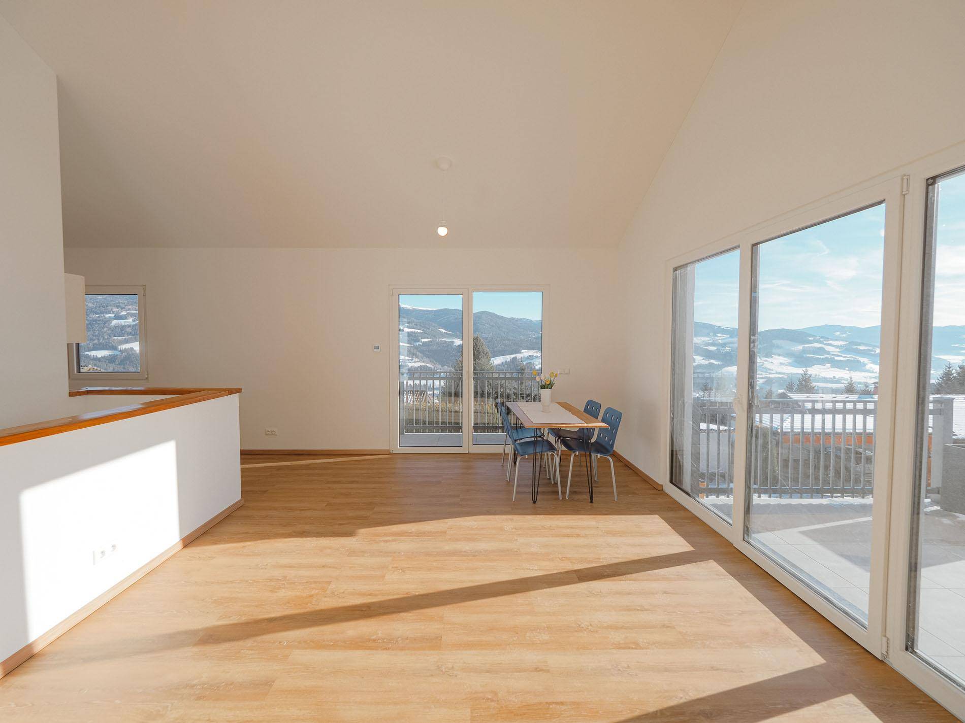 Geräumiger Wohnbereich mit weitem Blick auf die Berge und viel Tageslicht durch große Fenster.