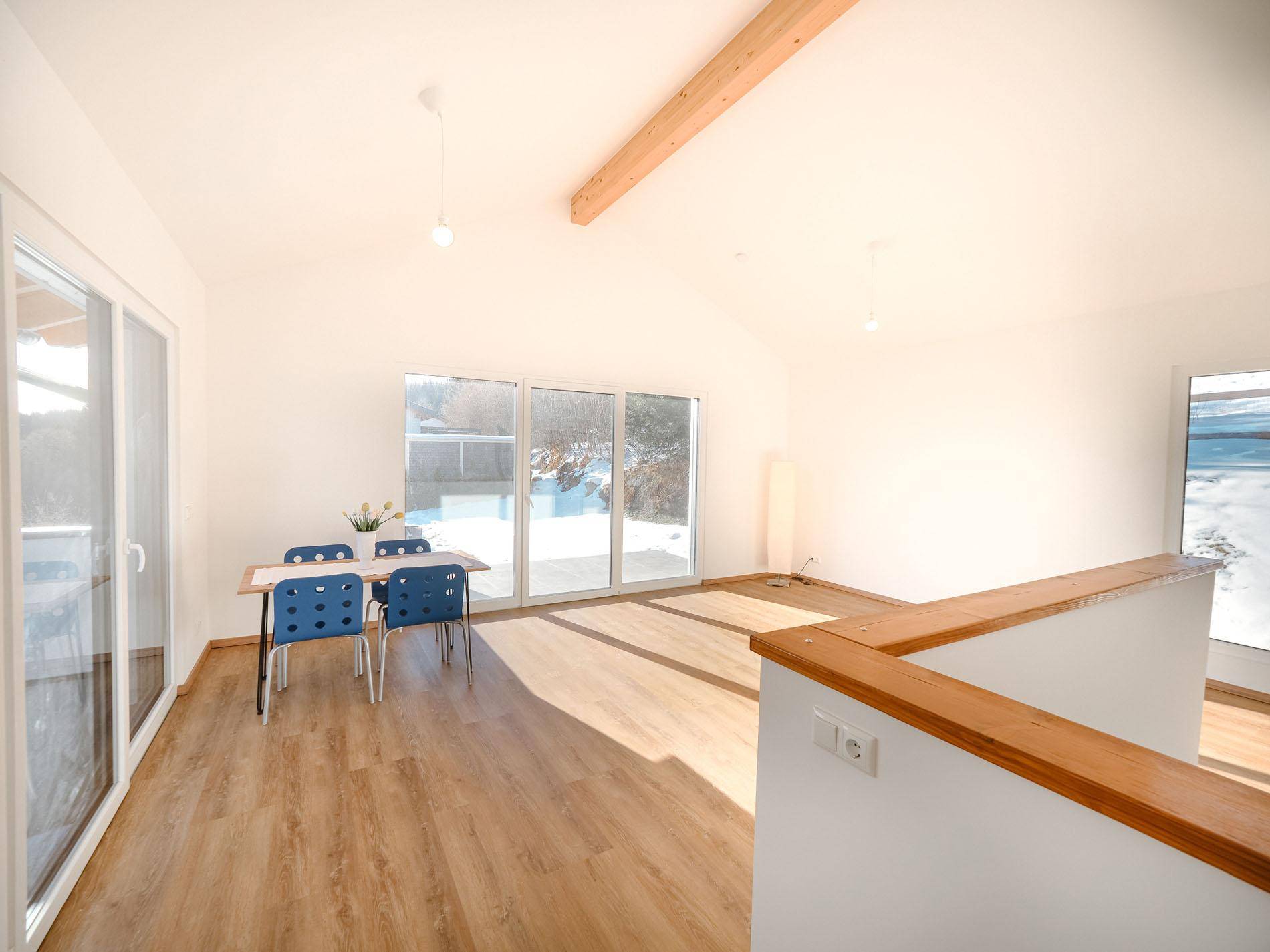 Heller Wohn-Essbereich mit Holzboden, hohen Decken und Zugang zum Balkon.