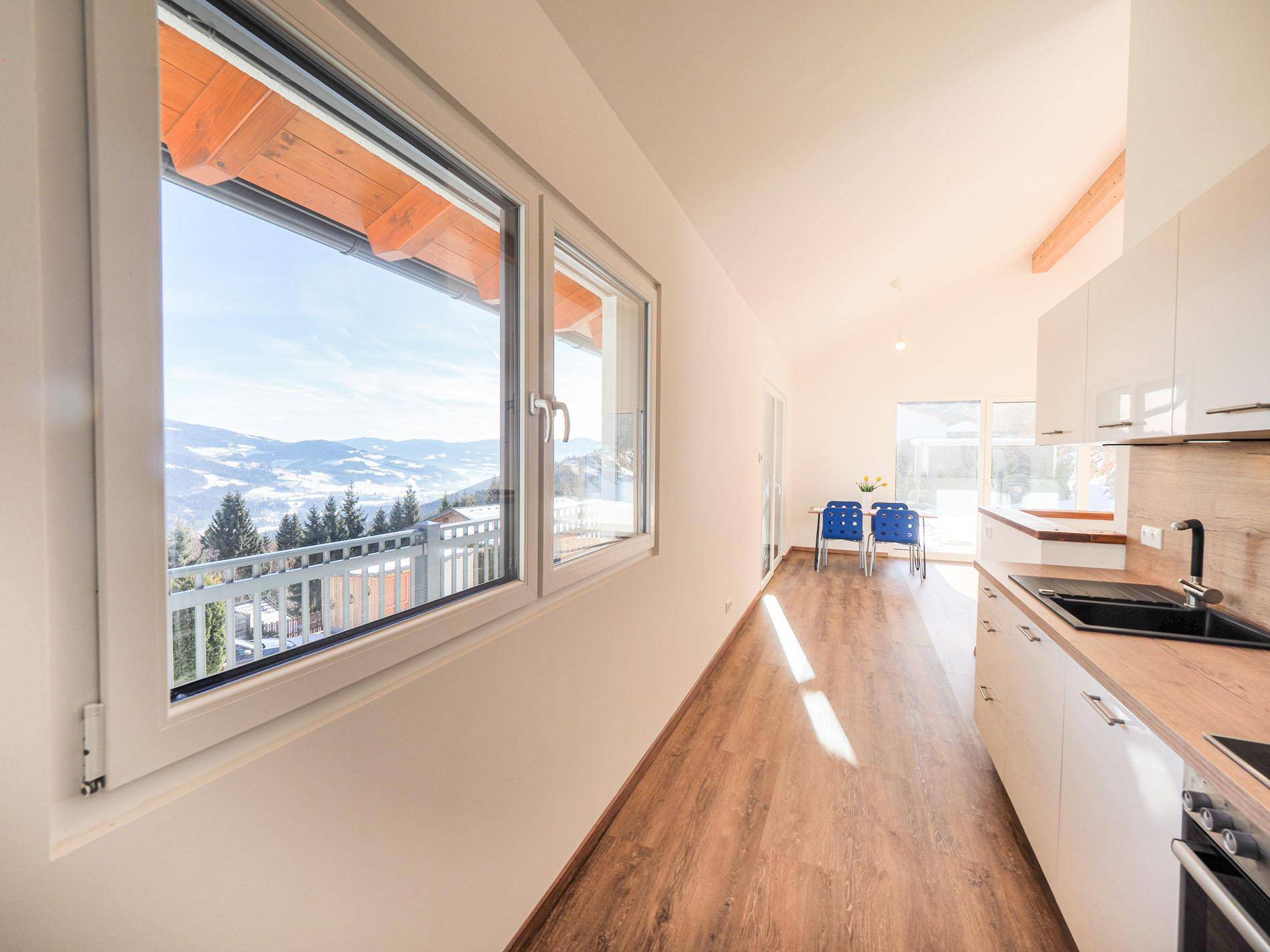 Moderne Küche mit Bergblick durch große Fenster und hellem Holzboden.