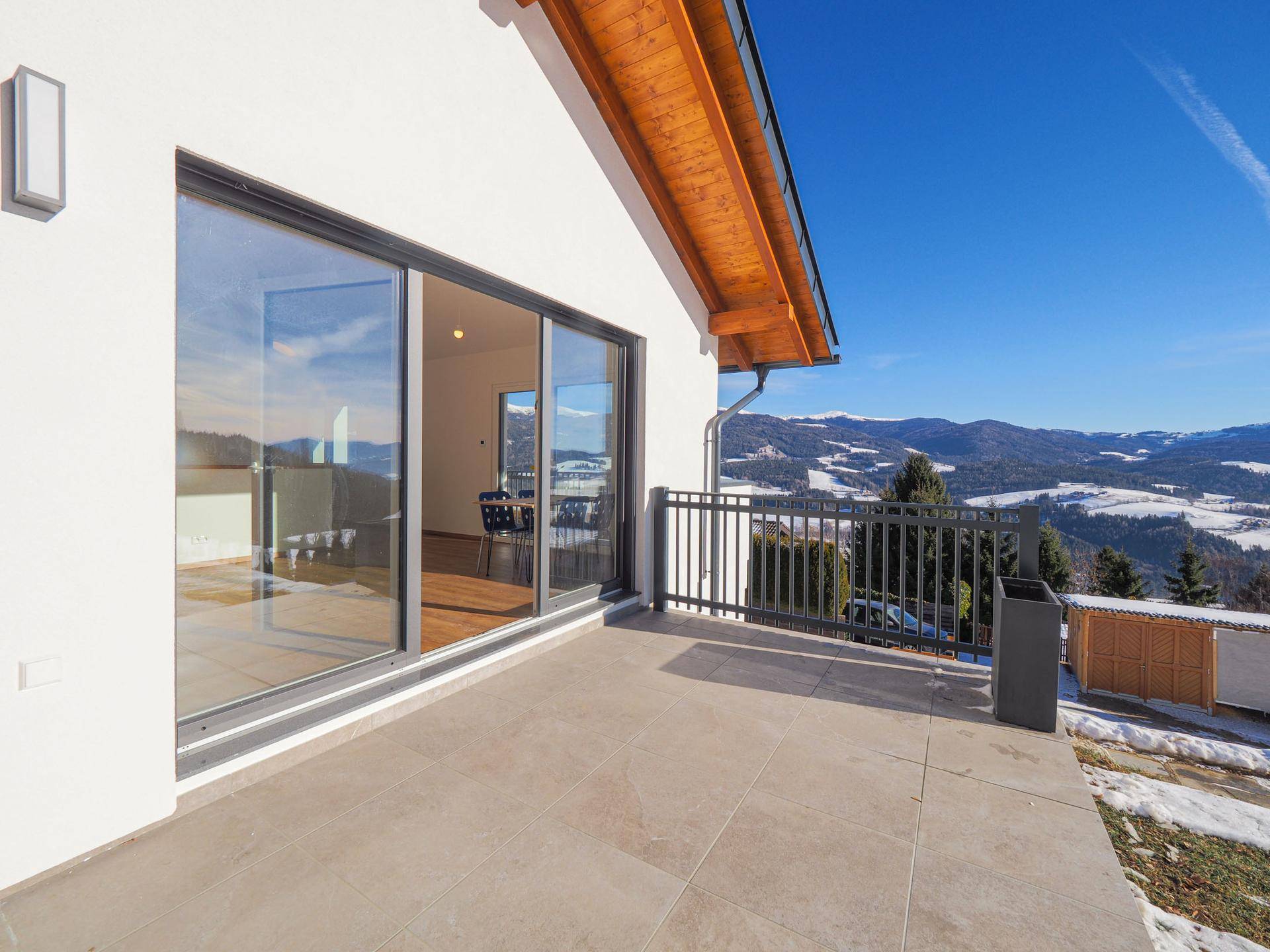 Geräumige Terrasse mit Fliesenboden und weitem Blick auf die verschneite Berglandschaft.