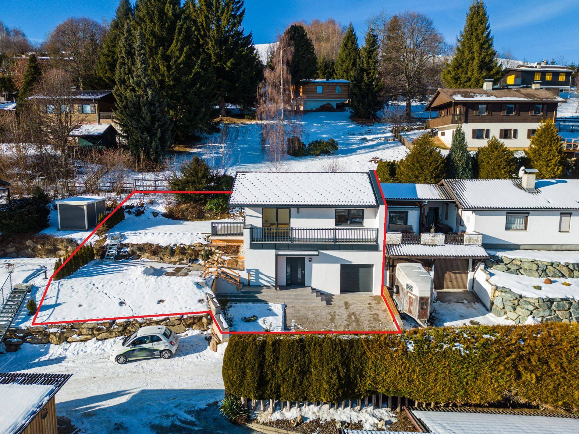 Luftaufnahme des Hauses mit Grundstücksgrenzen, Balkon und verschneitem Gartenbereich.