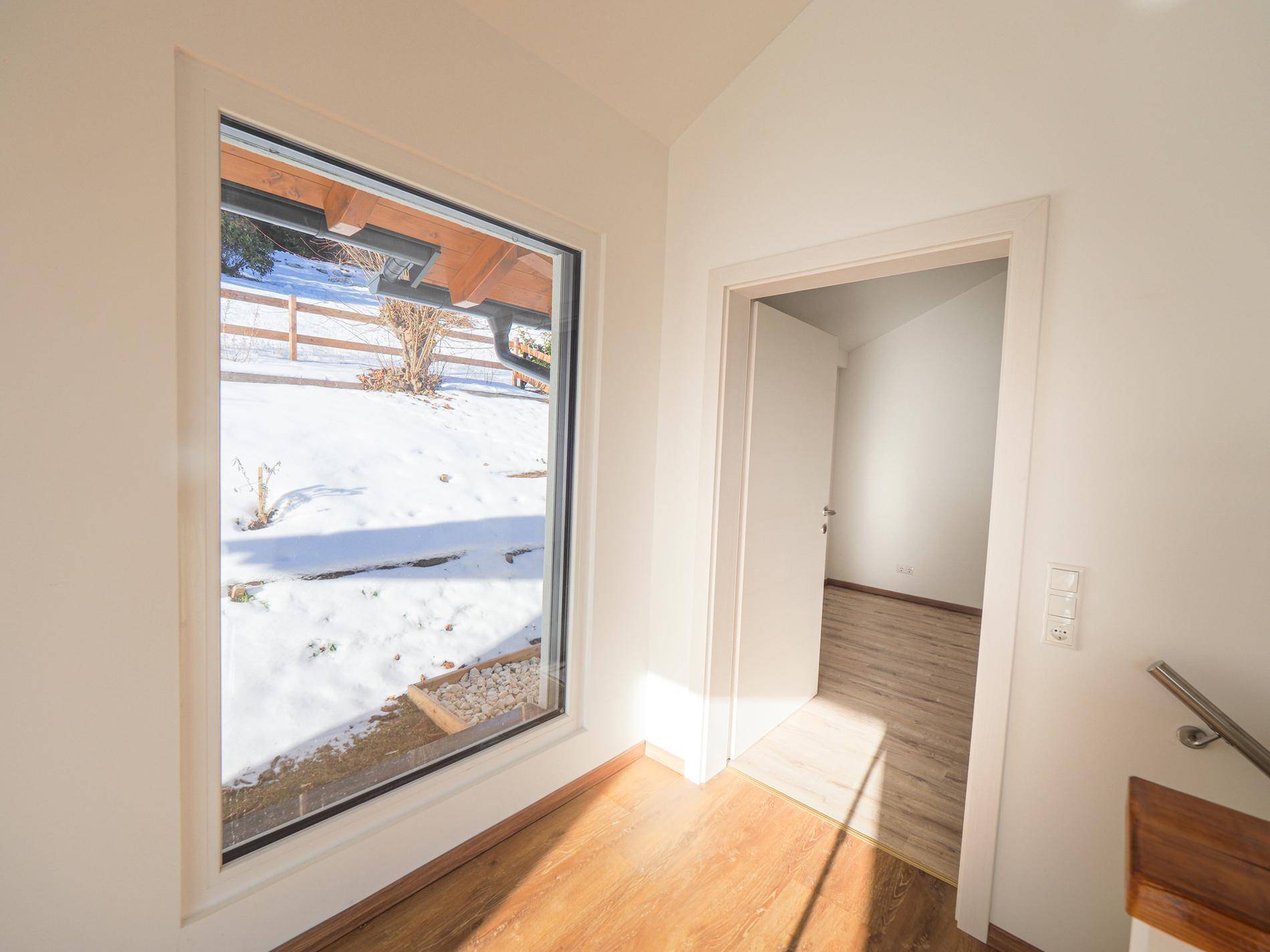Heller Flur mit großem Fenster, das den Blick auf die verschneite Außenanlage freigibt.