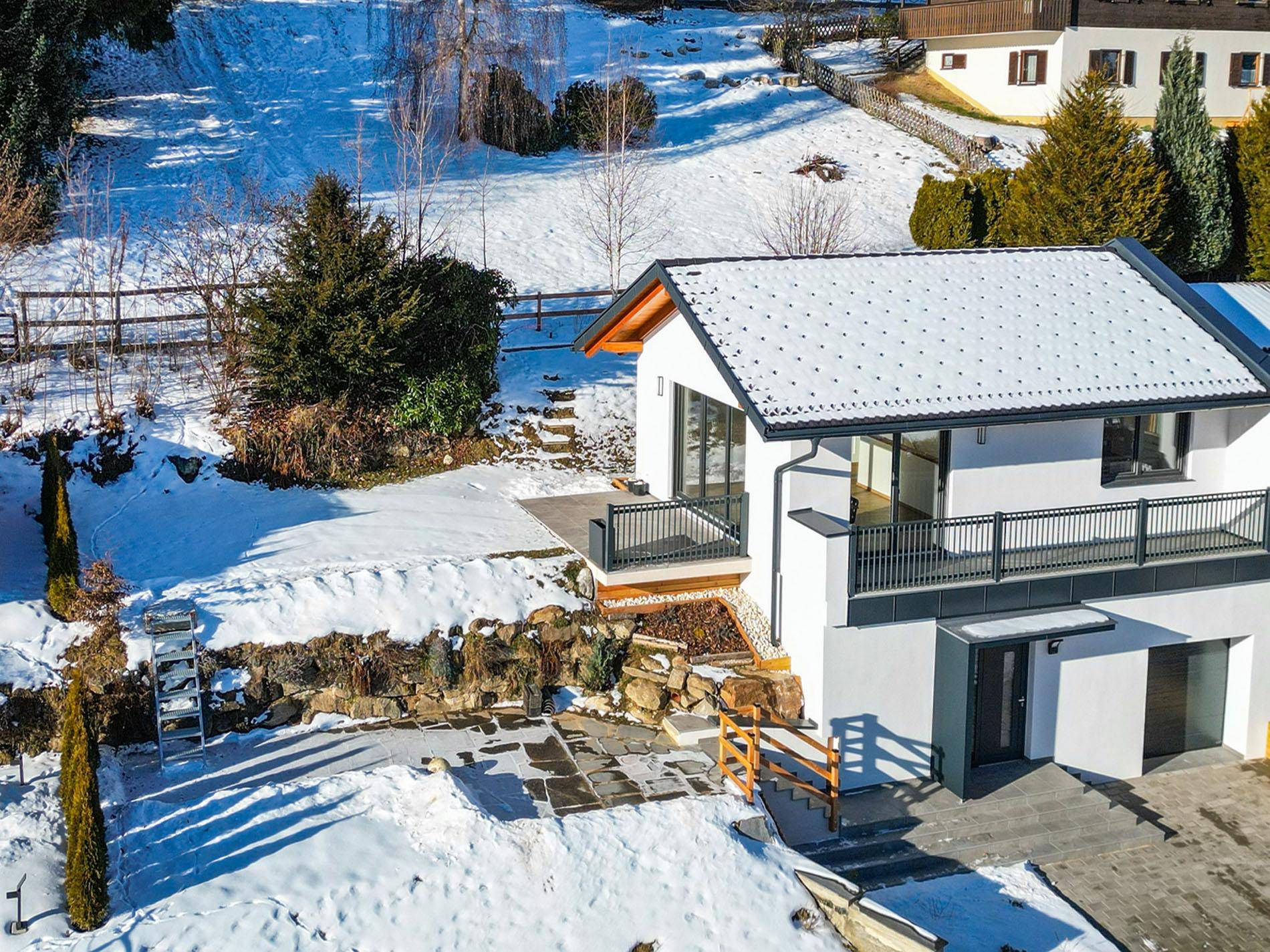 Luftaufnahme des modernen Hauses mit verschneitem Gartenbereich und umliegender Natur.