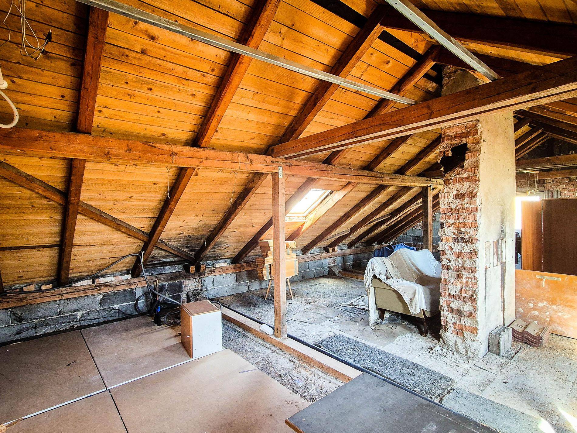 Unausgebauter Dachboden mit sichtbaren Holzbalken und Dachfenster, bereit für einen Ausbau.