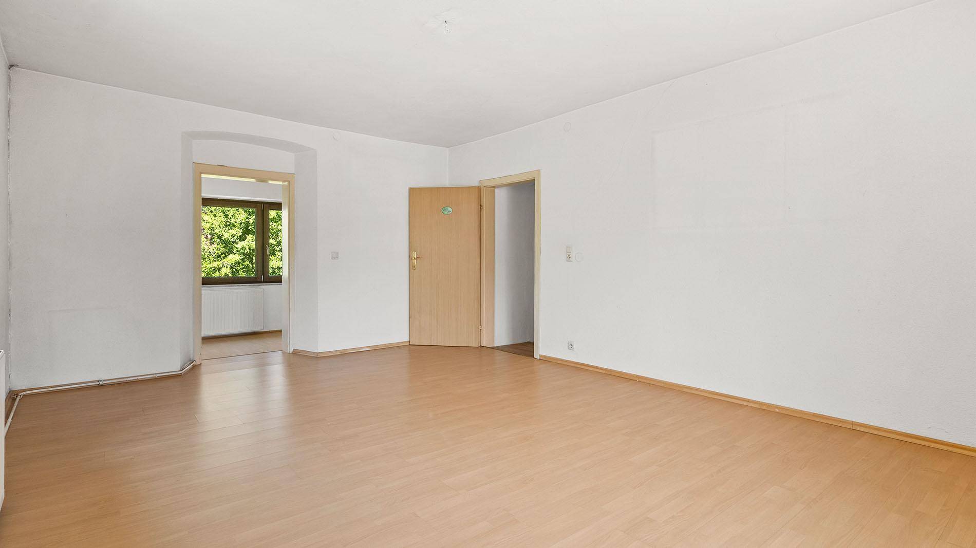 Heller Wohnraum mit Holzboden und Durchgang zu einem weiteren Zimmer.