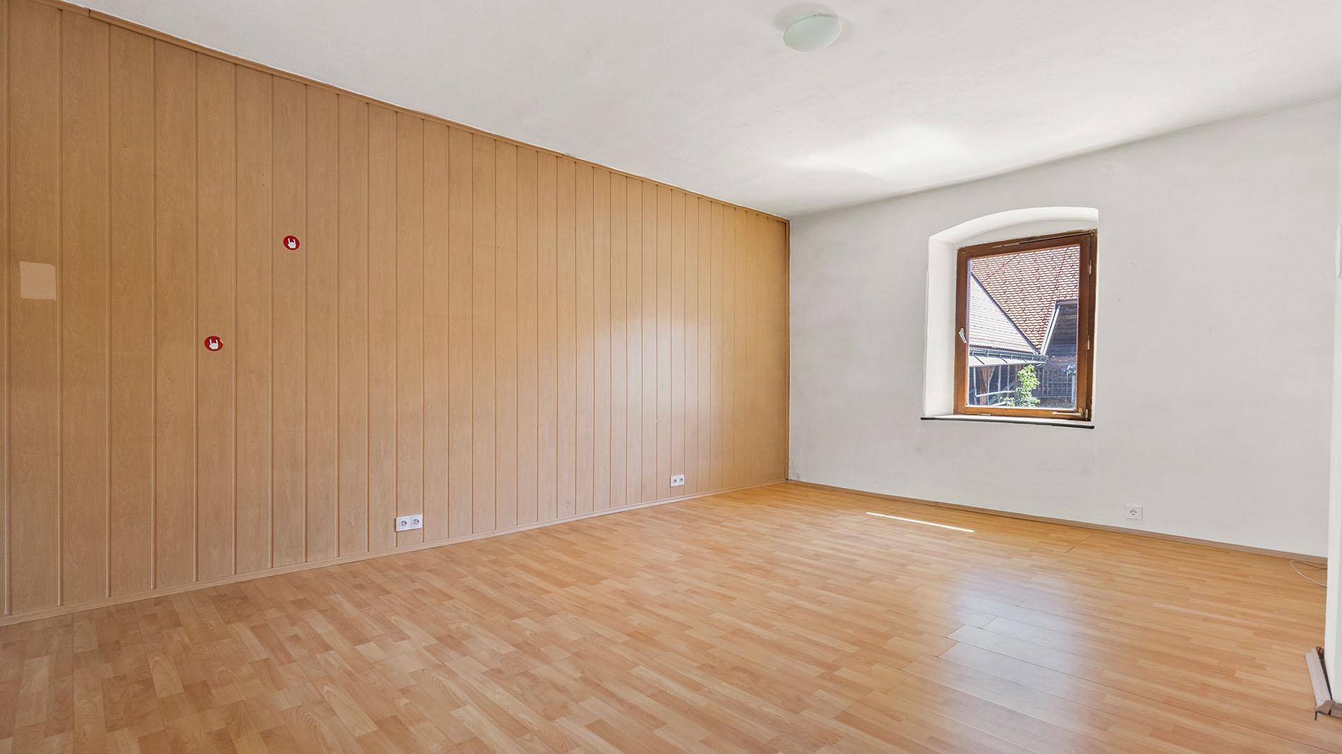 Wohnzimmer mit Holzboden und einer Wandverkleidung aus Holzpaneelen.