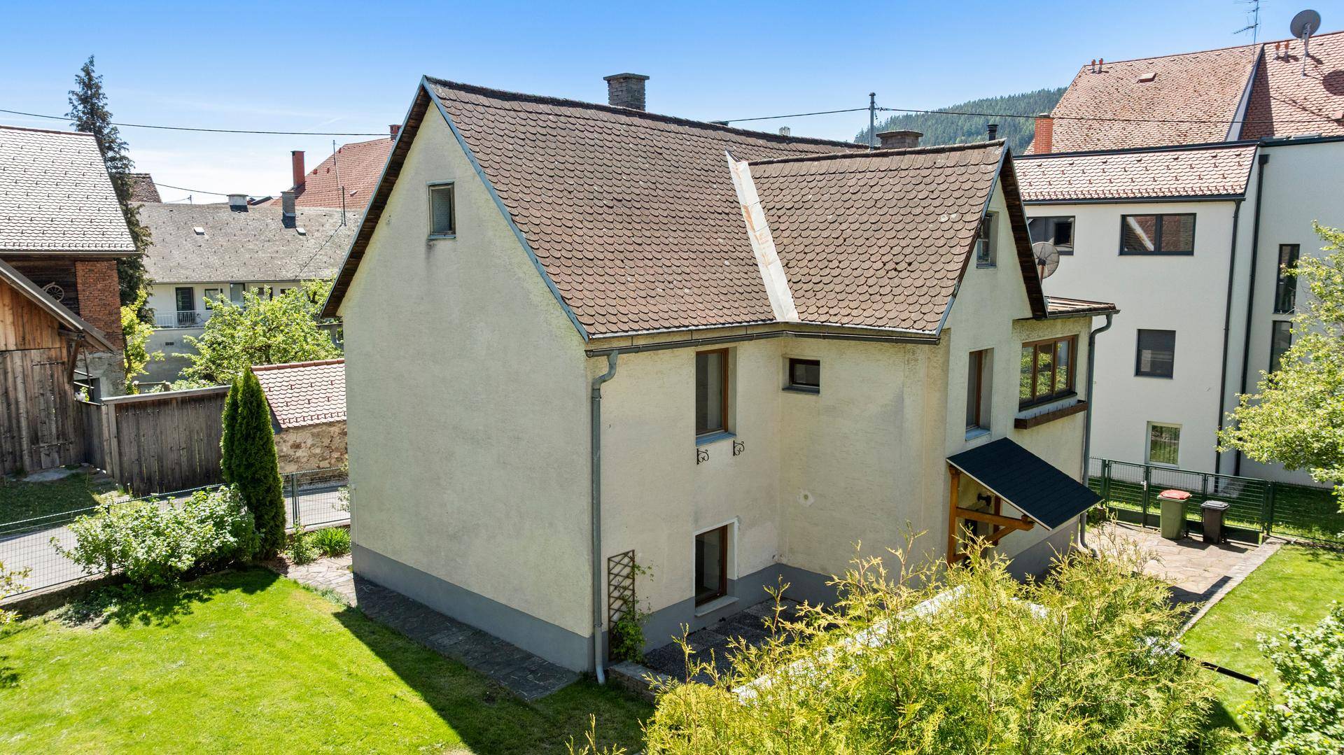 Seitenansicht des Hauses mit grünem Rasen und Blick auf die Nachbarschaft.