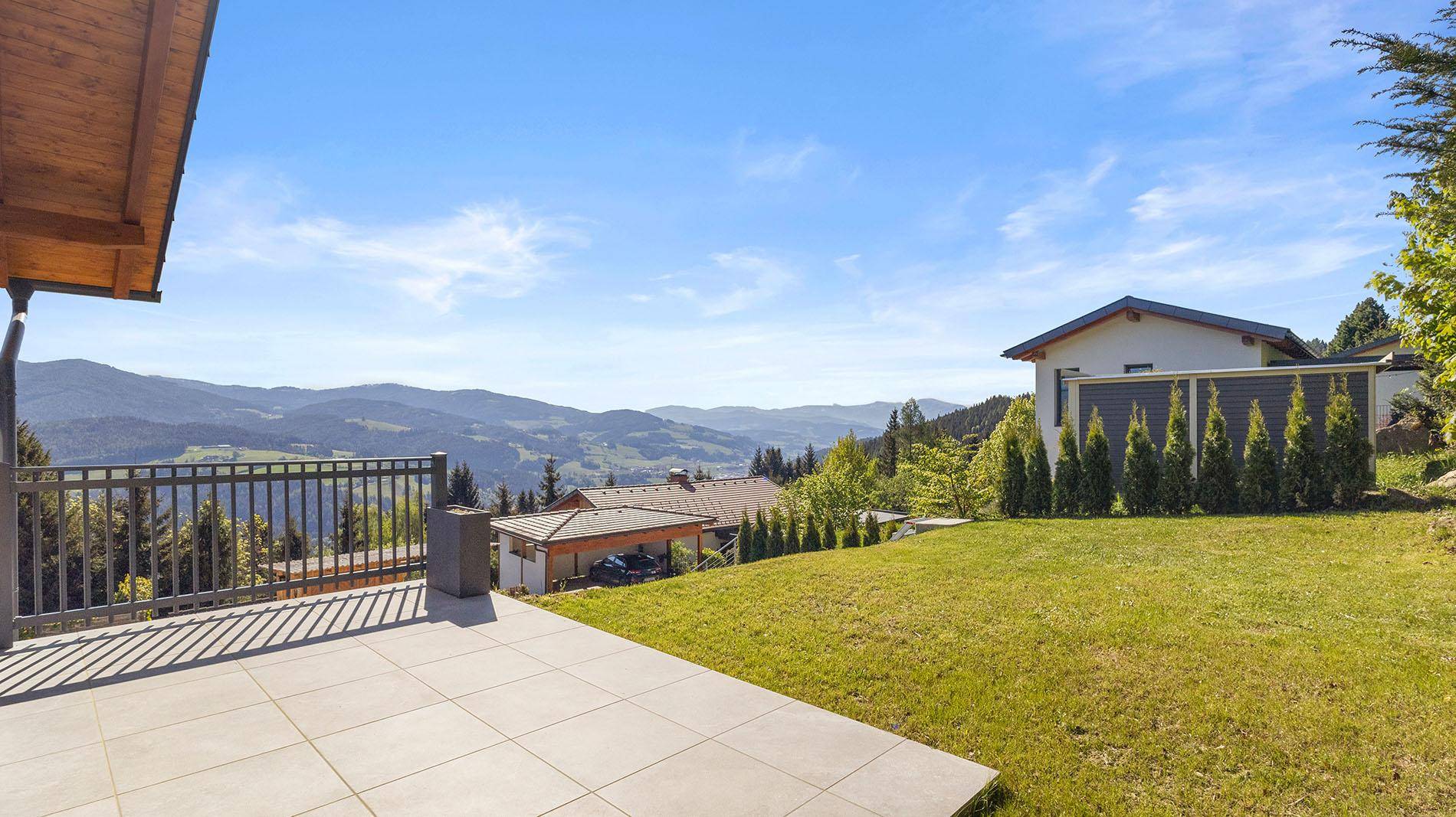 Sonniger Terrassenbereich mit Fliesenboden und atemberaubendem Blick auf die umliegenden Berge.