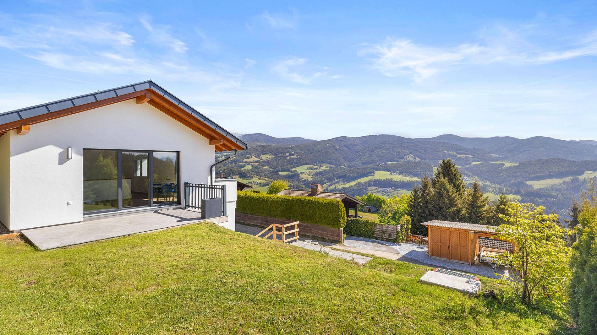 Großer Rasenbereich mit Terrasse und weitem Blick auf die malerische Berglandschaft.