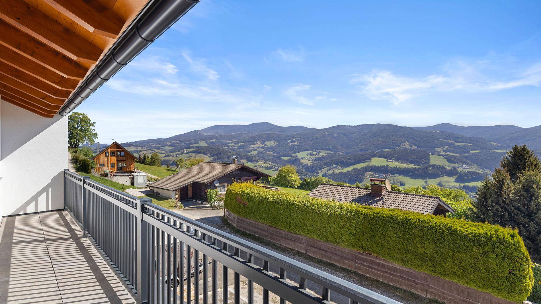 Heller Balkon mit Panoramablick auf die grünen Hügel und Berge in der Ferne.