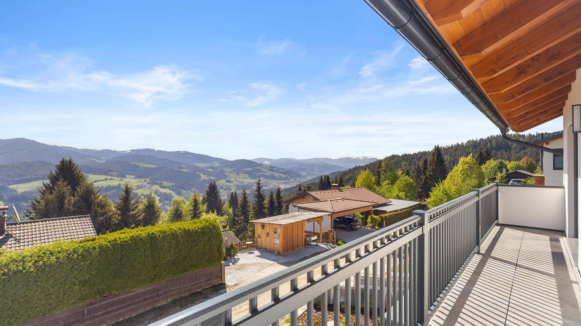 Geräumiger Balkon mit Fliesenboden und weitem Blick über die umliegende Berglandschaft.