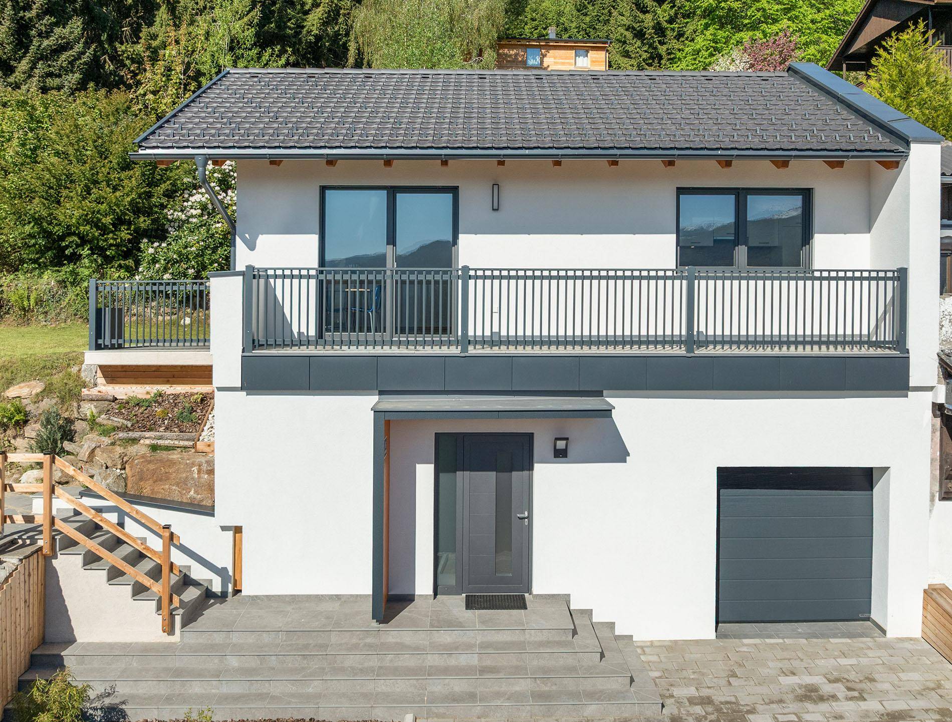 Vorderansicht des modernen Hauses mit Balkon, Garage und Eingangsbereich.