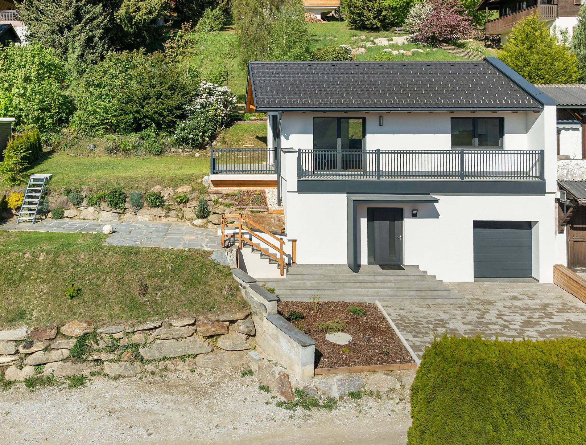 Das moderne Haus ist in eine grüne Hanglage eingebettet mit Zugang zum Garten.