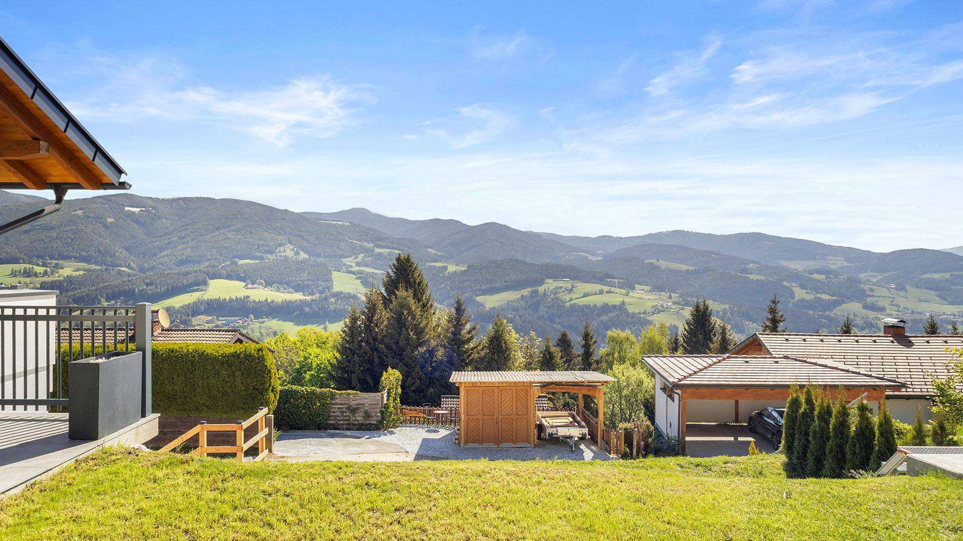 Gepflegter Garten mit Rasenfläche und weitem Panoramablick auf die grüne Berglandschaft.