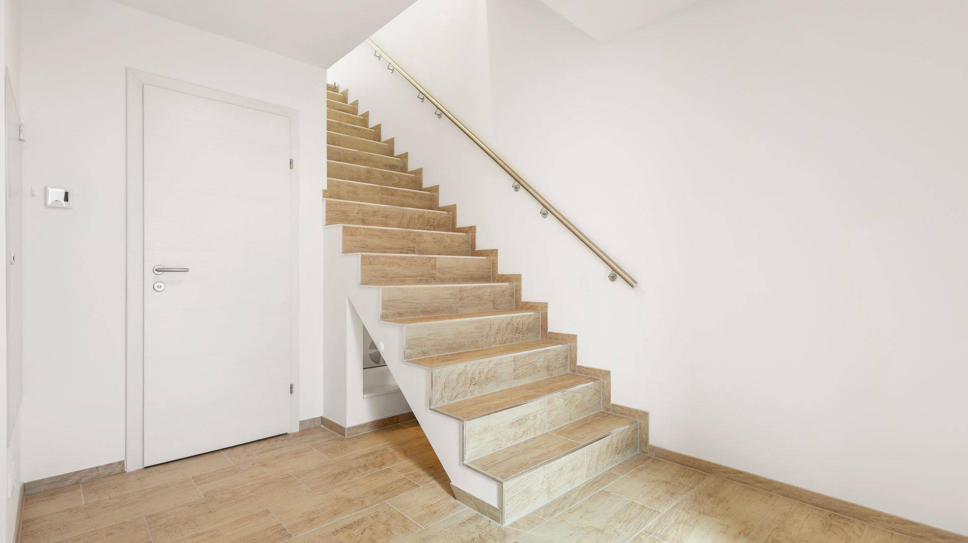 Heller Flur mit Holztreppe und Fliesenboden, der die Etagen verbindet.