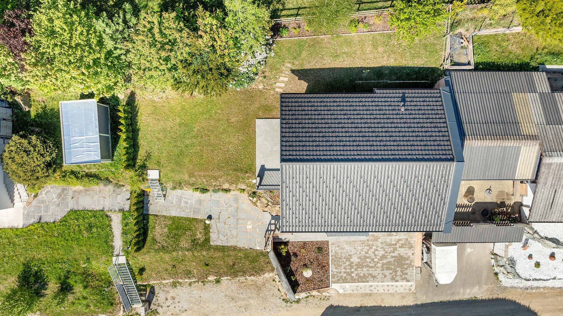 Draufsicht auf das Haus mit Garten, Terrasse und einem kleinen Gewächshaus.