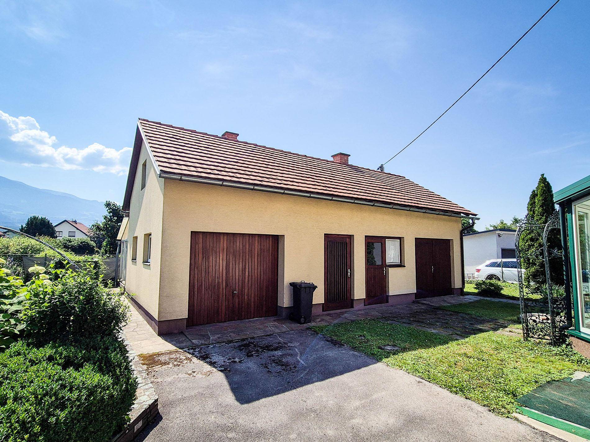Separate Garage mit zwei Holztoren und angrenzendem Gartenbereich.