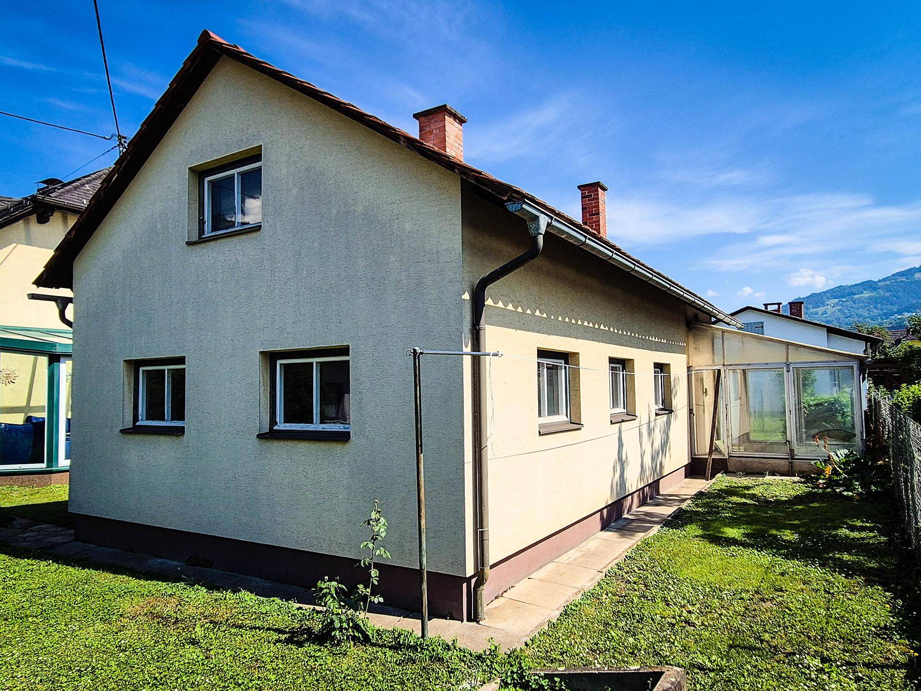 Rückansicht des Hauses mit Gartenfläche und Blick auf die umliegende Landschaft.