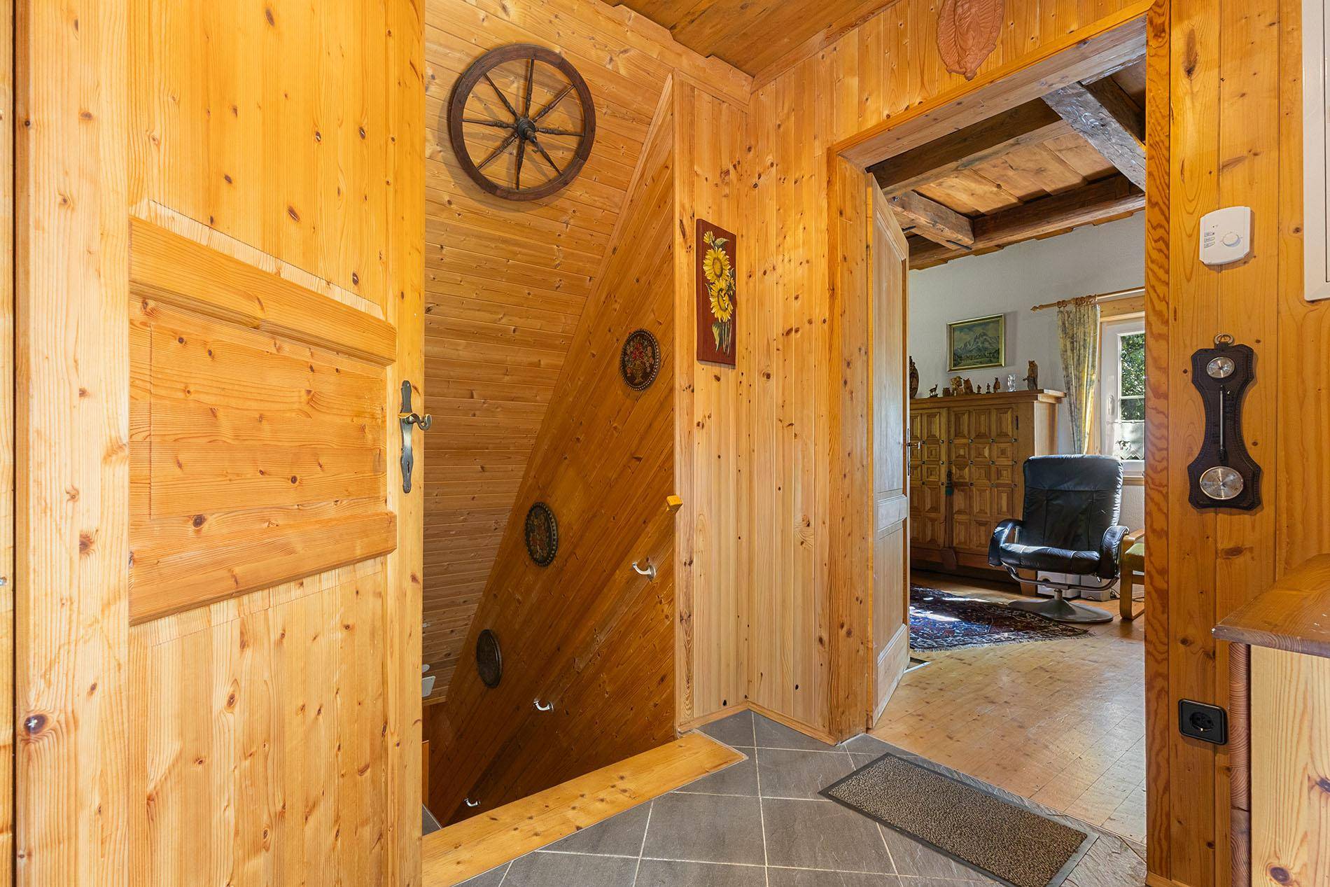 Rustikaler Flur mit Holzvertäfelung und Treppe, die in die oberen Stockwerke führt.