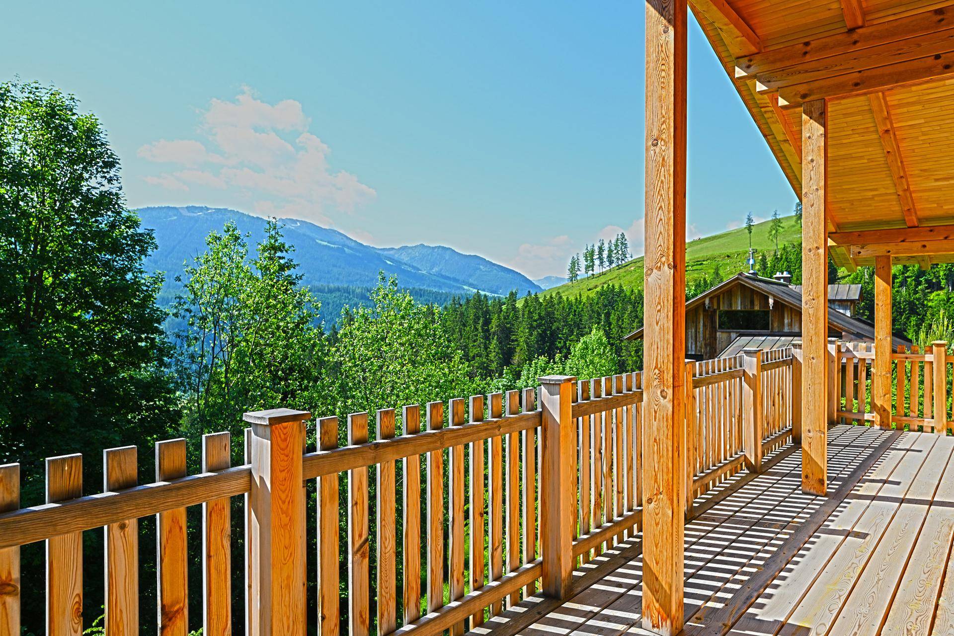 Geräumiger Holzbalkon mit traditionellem Geländer und spektakulärem Blick auf die Bergwelt.