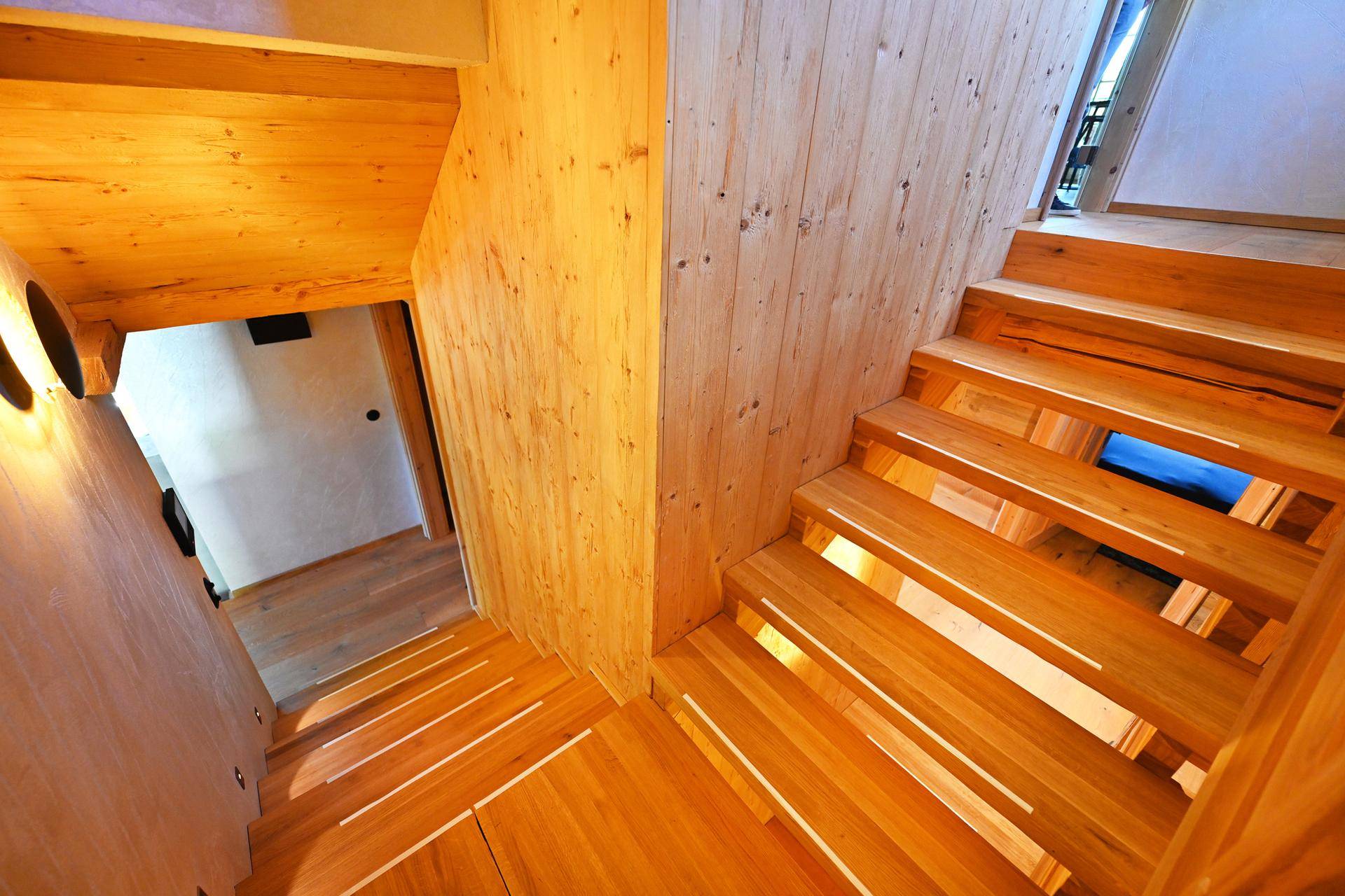 Elegante Holztreppe mit integrierter Beleuchtung, die die verschiedenen Ebenen des Hauses verbindet.