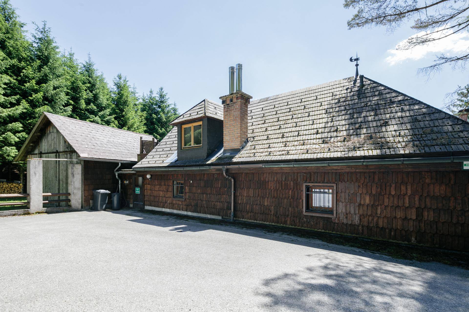 Seitenansicht eines Gebäudes mit Holzschindelfassade und einem angrenzenden Schuppen.