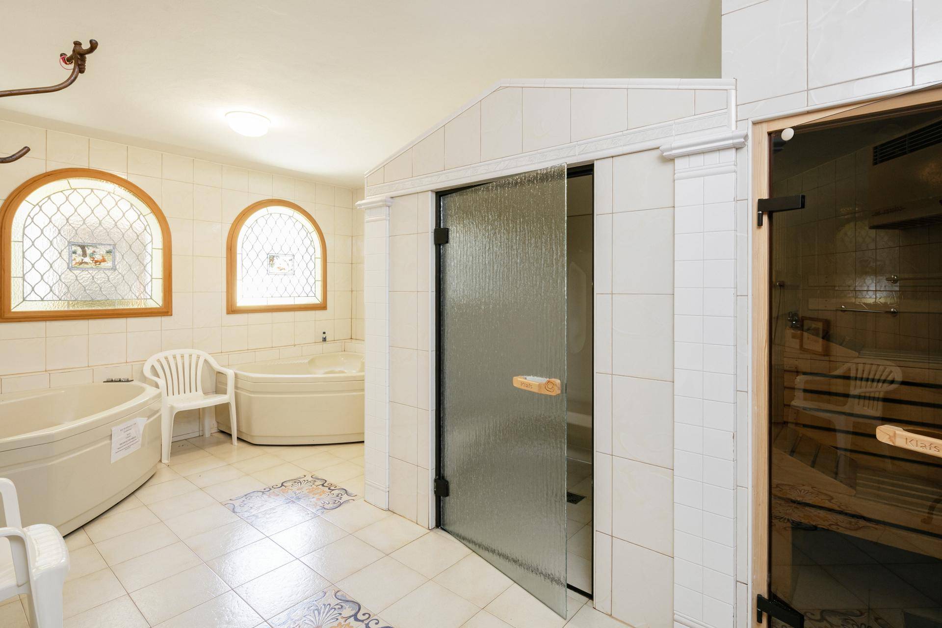 Wellnessbereich mit zwei Whirlpools, gefliesten Wänden und einer Saunakabine für Entspannung.